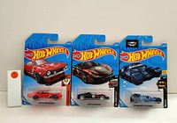 Three Hot Wheels cars in original blister card packaging: red 1967 Pontiac Firebird, black Porsche 918 Spyder, and black Batmobile from DC Comics.