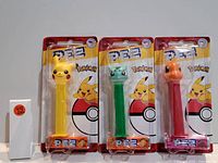 Photo showing three new PEZ dispensers featuring Pokemon characters Pikachu, Bulbasaur, and Charmander, each sealed in original blister pack packaging.
