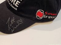 Close-up photo of the cap's brim with silver autograph visible.