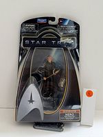 Front view of sealed Star Trek Nero figurine in black box with plastic window, showing figure and staff.