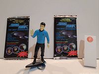 Photo showing Star Trek The Next Generation figure standing on display stand with two unopened collectible figure packages #62 behind it.