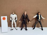 Photo of three Star Wars figures: Luke Skywalker in Stormtrooper outfit, Anakin Skywalker in dark Jedi robes, and Han Solo with a blaster and vest.