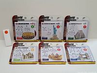 Front view of 7 World Architecture model kits in original packaging: Colosseum, Statue of Liberty, Mayan Pyramid, Taj Mahal, Sydney Opera House, Tower Bridge.