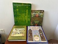 Top-down photo showing four vintage Arts and Crafts Movement books, different colors and sizes.
