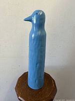 Blue ceramic penguin figurine viewed front profile showing tall slender body and pointed beak with smooth light blue glaze.
