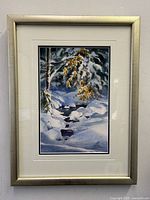 Framed watercolour painting showing snowy winter scene with rocks and pine tree branches dusted with snow.