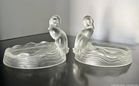 Pair of frosted satin glass duck figural trinket dishes with wavy edges and dotted inner base pattern, shown side by side.
