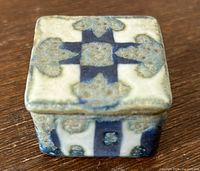 Top view of the square ceramic miniature lidded box showing the blue cross-like pattern and textured glaze