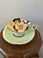 Tea cup and saucer set placed on wooden table highlighting floral design and scalloped rim