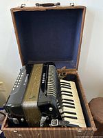 Accordion in open vintage case showing the layout of the instrument and case interior.