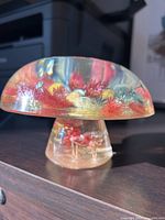 Side angle of clear Lucite mushroom showing colorful dried flowers inside the cap and part of the stem.
