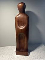 Front view of wooden figure sculpture illustrating smooth contours and teak material.