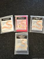 Four unopened packages of Shapermint Essentials: three scoop neck camisoles in white, pink, navy and one pair of black high-waisted shaper shorts.