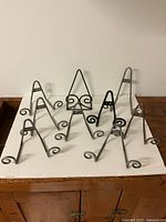 Nine metal display stands arranged on a white surface, showing sizes and swirl design details.