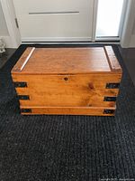 Full front view of early 1900s pine chest with iron corner brackets and visible keyhole on front panel.