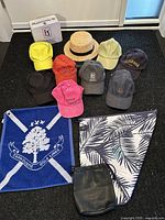 Full lot showing various golf caps, two golf towels, a woven hat, and golf pouch arranged neatly.