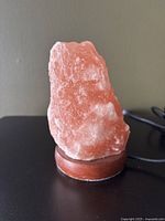 Close-up front view of pink Himalayan salt lamp on a wood base.