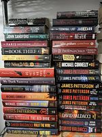 Photo showing stacked fiction books by various authors including Preston & Child, Lisa Jackson, John Sandford, Bryn Turnbull, Markus Zusak, David Bell, Nelson DeMille, Madeline Thien, and Kate Elizabeth Russell.