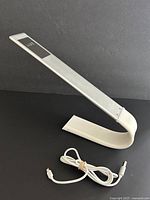 LUXE LED lamp displaying its modern curved design and charging cable included.