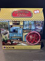 Front view of the sealed puzzle box showing the Country Kitchens scene, 500 pieces, and the cookie cutter attached.