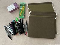 Photo of various pens, wood pencils, and olive green hanging folders letter size