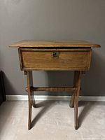 Front view of the vintage solid oak table showing drawer with brass keyhole and curved legs with decorative cutouts