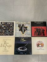 Top view of six vinyl record album covers featuring Grand Funk Railroad, Alice Cooper, J. Geils Band, Three Dog Night, Ian Thomas, and Queen.