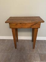 Front view of vintage wooden side table showing golden patina finish and four tapered legs.