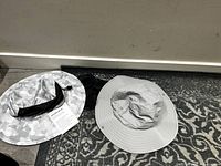 Two wide-brim ladies hats - white camo with black band and solid light gray.