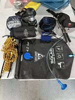 Photo showing the overall items for camping including solar camp shower, rope, jacket, lantern, and accessories on table