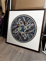 Framed circular silkscreen print leaning against wall on floor