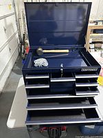 Open toolbox showing lid compartment, removable tray, mallet, chain and partially open drawers