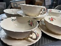 Photo showing stack of soup bowls and saucers highlighting embossed eyelet pattern and rose design