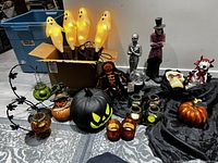 Wide shot of all Halloween decorations showing ghosts, pumpkins, candle holders, and figurines grouped together on floor.