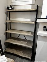 Full view of five-shelf ladder-style unit against wall