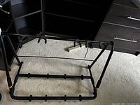 View of black foldable guitar rack showing padded hanging hooks and rubberized guitar supports.