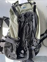 Mountain Equipment Co-op hiking backpack lying flat showing front with bungee cord, external pockets, and bottom part of backpack.