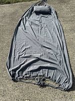 Full view of the gray fabric hammock with a matching pillow laid flat on the ground.