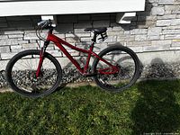 Full side view of red Specialized mountain bike leaning against exterior wall