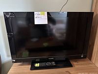 Front view of Sony Bravia 32 inch TV with remote on stand showing model and branding.