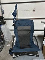 Front view of blue Sport-Brella beach chair with mesh seating and upright folded umbrella attached to right side.