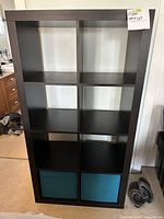 Front view of the black cube shelf with 8 compartments and 2 blue fabric drawers.