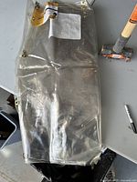 Clear vinyl Tillman welding curtain folded on table with Rock Forge sledge hammer beside it