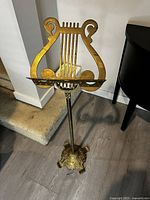 Full view of vintage brass music stand featuring lyre shaped top and heavy base.