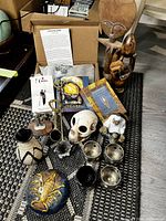 Overview of all items showing white sage pouch, oracle cards, African sculptures including Akuaba doll and unity globe, scorpion paperweight, carved skull, candle holders, and ceramic vase.