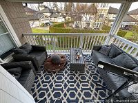 Wide view of balcony showing entire furniture set on outdoor rug