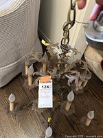 Chandelier laying on a wooden floor showing 8 arms with candle-style light covers and ornate metal leaves