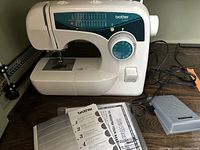 Brother XL-2600i white sewing machine on table with foot pedal and instruction manual beside it