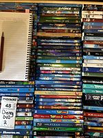 Top view of stacked Disney and Pixar Blu-Ray and DVD cases showing titles and variety of movies in collection.