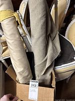 Two fabric rolls in a cardboard box, one light beige satin and a textured neutral fabric.